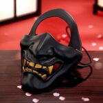 Demi masque japonais Hannya noir en matière rigide avec dents dorées et expression démoniaque traditionnelle