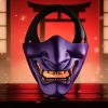 Demi masque japonais Hannya violet en plastique avec dents dorées et sangle noire devant un décor traditionnel rouge