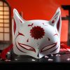 Masque japonais Kitsune blanc en céramique avec motifs rouges et spirale centrale, décor traditionnel renard sacré