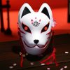 Masque japonais Kitsune roublard blanc avec motifs rouges et noirs, décorations rouges suspendues et petits grelots dorés
