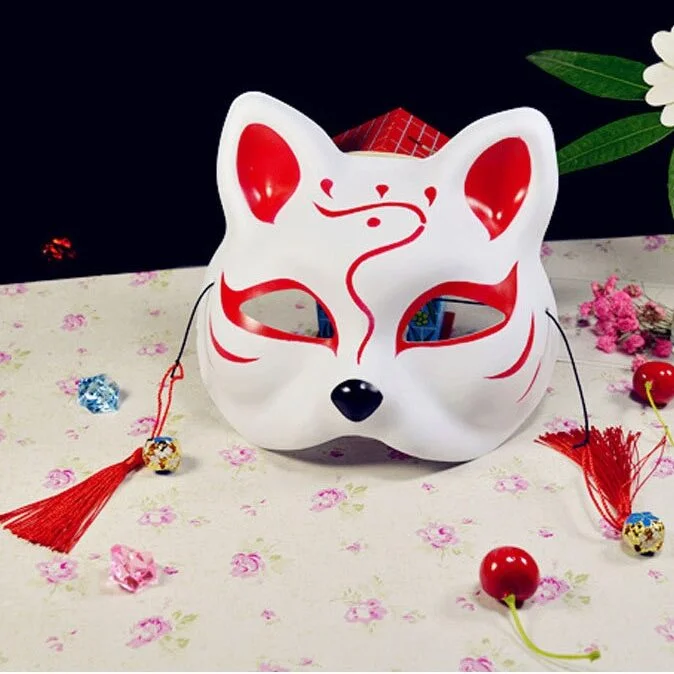 Masque japonais Kitsune l'Espiègle blanc avec motifs rouges et noirs, décor renard sacré avec pompons rouges, vue de face