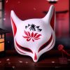 Masque japonais Kitsune fleuri en céramique blanche avec motifs rouges et noirs représentant une fleur sur le front, décor traditionnel de renard sacré