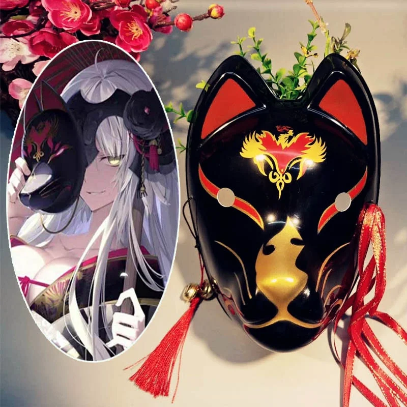 Masque japonais kitsune noir en résine avec motifs dorés et rouges, orné de pompons rouges, vue de face
