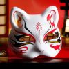 Masque japonais Kitsune tribal blanc avec motifs rouges, noirs et dorés, forme de renard sacré, décoration traditionnelle