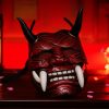 Masque japonais Oni rouge en bois sculpté avec grandes défenses blanches et cornes noires, décor traditionnel démoniaque
