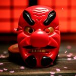 Masque japonais Tengu rouge en bois avec sourcils et moustache noirs, nez proéminent et expression traditionnelle